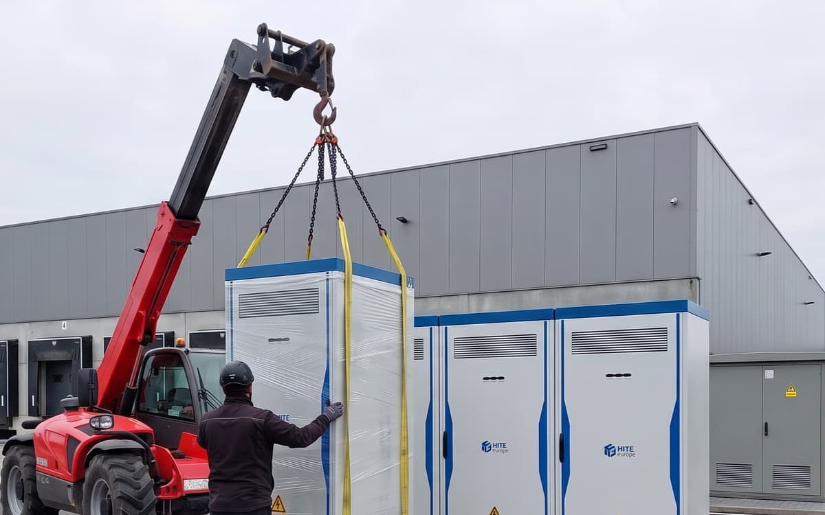 Een verreiker zet een ingepakte batterijkast naast twee kasten die al staan